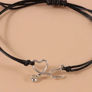Dettaglio del bracciale regolabile in corda nera con ciondolo stetoscopio a cuore