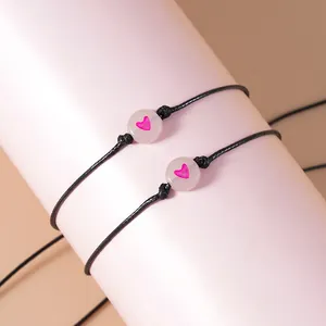 Close-up van zwarte gevlochten vriendschapsarmbanden met roze hartkralen op een display