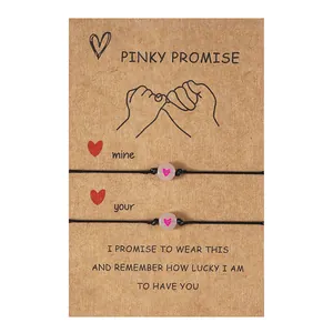 Detail van roze hartkralen op zwarte koordarmbanden met een Pinky Promise geschenkkaart