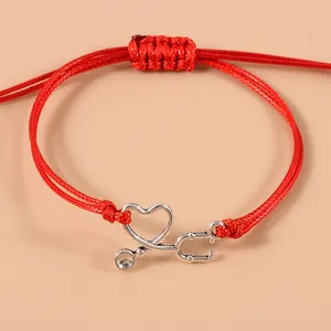 Dettaglio del bracciale in cordino rosso con ciondolo stetoscopio in argento a cuore