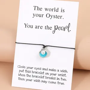 Handgewebtes Armband mit blauem Muschelanhänger und Perle auf Geschenkkarte