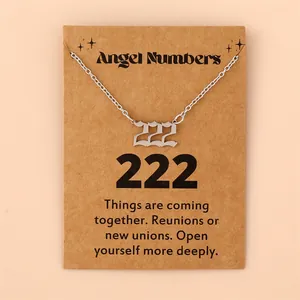Vue macro du pendentif chiffre ange 222 argenté sur une carte cadeau kraft marron