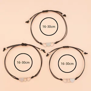 Three sisters heart charm bracelets set in black woven cord on light pink background