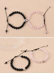 Close-up of magnetic heart charms connecting black and pink beaded couple bracelets