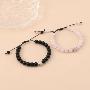Close-up of magnetic heart couples bracelets with pink and black beads and woven ropes