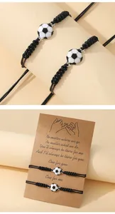 Macro detail of adjustable braided football friendship bracelets with soccer charms on card