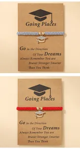 Close-up of woven graduation bracelets with rhinestone-set mortarboard charms on cards