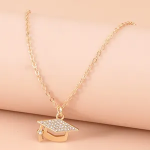 Golden graduation cap necklace with sparkling rhinestones on minimalist pedestal