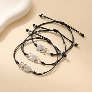 Set van drie zwarte gevlochten armbanden met in elkaar grijpende hartvormige bedeltjes