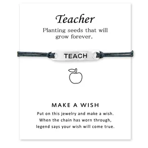 Detail des TEACH-Anhängers auf schwarzem Armband mit einer Grußkarte für Lehrer