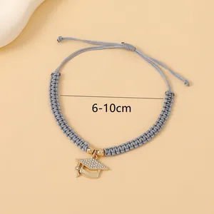 Adjustable woven bracelet with gold graduation cap pendant and diamond-like accents