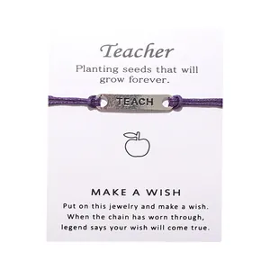 Detail eines lila geflochtenen Armbands mit TEACH-Metallplatte auf Wunschkarte