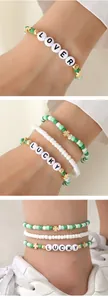 Détail de bracelets et chevillières en perles avec trèfle porte-bonheur et perles LOVER