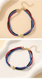 Macro detail of multi-layer seed bead bracelet with gold heart charm and lobster clasp