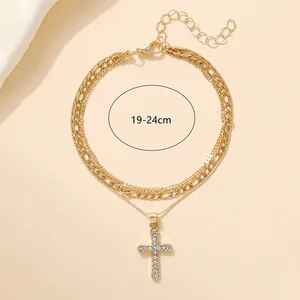 Double-layered gold chain bracelet with a sparkling rhinestone-encrusted cross pendant