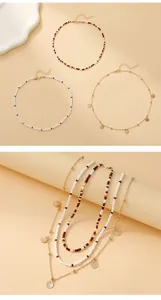 Detail of layered bohemian seed bead necklaces with gold shell charms and round pendants