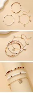 Detail of layered bohemian bead bracelets and gold metal chain with scallop pendants