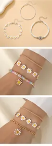Détail de l'ensemble de bracelets marguerite et tournesol avec chaîne dorée et perles émaillées