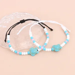 Detail van geweven schildpadarmbanden met gekleurde kralen en turquoise bedeltje