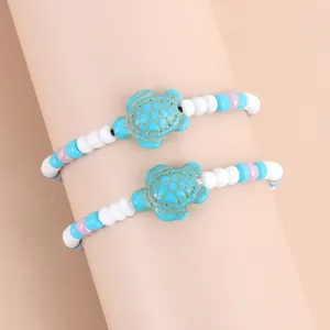 Detailopname van oceaanarmbanden met turkooizen schildpadden en pastelkleurige kralenset