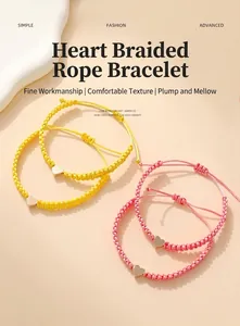 Detail of yellow and pink woven heart bracelets with adjustable gold charms