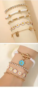 Detail of layered bohemian bracelets with sunflower charms, gold beads and faux pearls