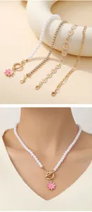 Detail of sunflower charm pearl bracelet and layered gold bead chains on model's wrist