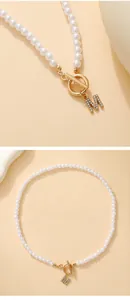 Detail view of pearl necklace with gold OT clasp and diamond-encrusted letter M pendant