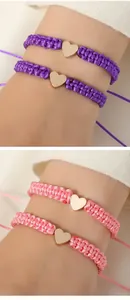 Macro detail of hand-woven purple and pink heart charm bracelets with metallic gold finish