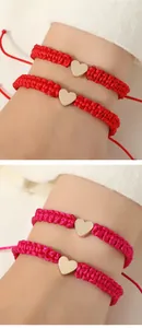 Detailed shot of handmade woven heart bracelets in vibrant red and magenta colors