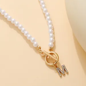 Elegant pearl necklace with crystal letter M pendant and gold OT toggle clasp