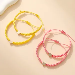 Set of four woven heart charm bracelets in pink and yellow with adjustable cords