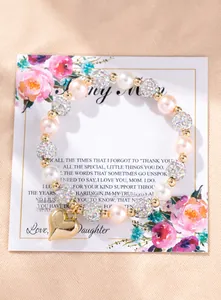 Close-up of pink pearl bracelet with gold heart charm on floral gift card background