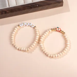Teacher clay apple beaded bracelets with wood beads and gold letters on soft background