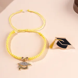 Graduation theme jewelry set with yellow braided bracelet and black enamel mortarboard pin