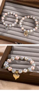 Detail of beaded bracelet with pearl beads, rhinestone disco balls and gold heart charm