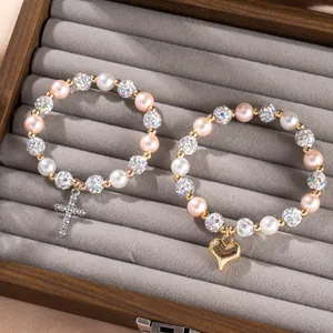 Pink and white pearl bracelet set with silver cross and golden heart charms in a wooden box