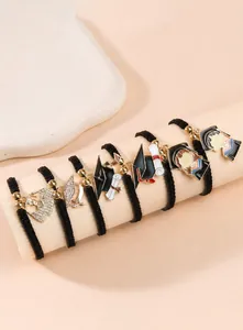 Detailed view of woven bracelets with graduation cap charms and enamel scroll pendants