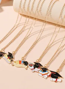 Detailed close-up of golden graduation necklaces with enamel mortarboard and scroll charms