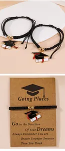 Detail of woven graduation bracelets with academic cap charms on a gift message card