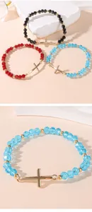 Detailed macro view of faceted crystal beads and a gold cross charm on an elastic bracelet