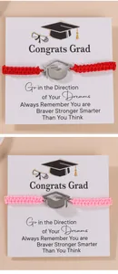 Close-up of red and pink braided graduation bracelets with silver mortarboard charms