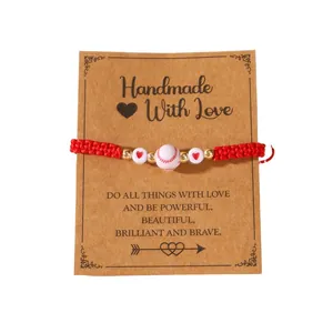 Handmade red braided cord bracelet with baseball and heart beads on a display card