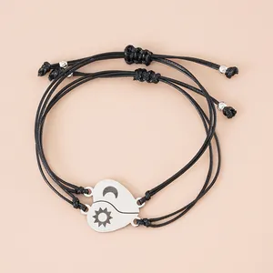 Detail van zon en maan hartbedeltjes aan verstelbare zwarte gevlochten koppelarmbanden