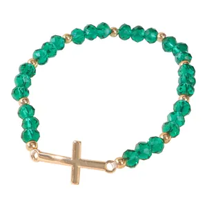 Green crystal beaded bracelet with golden stainless steel cross pendant on white background