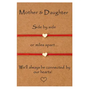 Détails des bracelets mère-fille en corde rouge avec breloques cœur doré sur carte cadeau