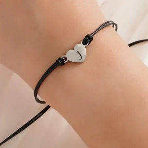 Close-up of adjustable black woven rope bracelet with silver heart charm engraved with J