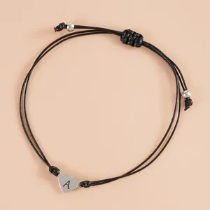 Minimalist black braided bracelet with silver heart pendant featuring letter A engraving