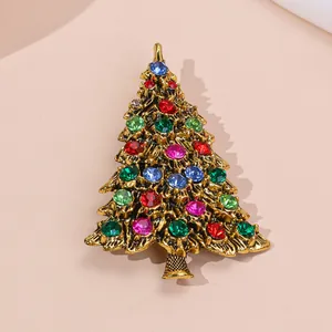 Exquisite gold alloy Christmas tree brooch with colorful rhinestones on a pink background