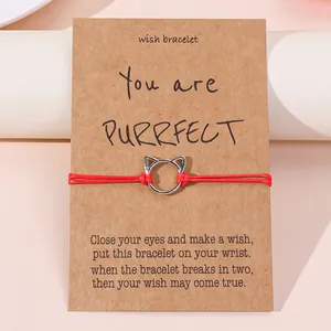 Minimalistische rode gevlochten kattenarmband op een kraft wenskaart presentatie